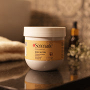 Serenade Moisture & Mood Body Butter with Ylang Ylang, Bergamot and Geranium essential oils placed in a warm setting for nourishing aromatherapy skincare